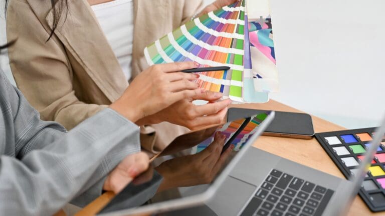Two of a graphic designers are discussing and planning the web colour for their project together.